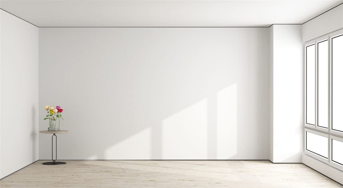 Witte wand met zonlicht, lichte houten vloer en een tafeltje met bloemen