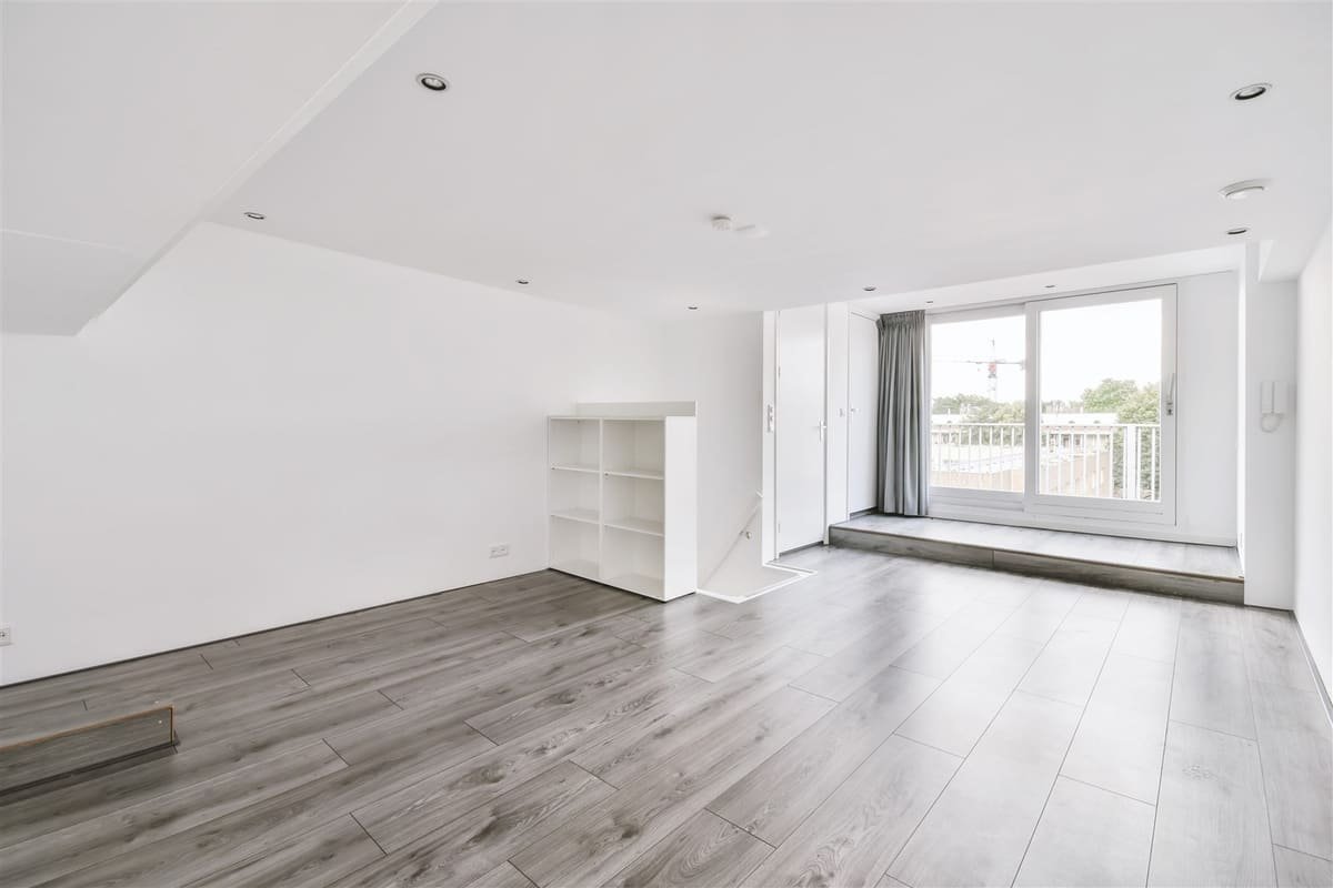 Woonkamer met witte wanden, plafond met inbouwspots en een grijze vloer